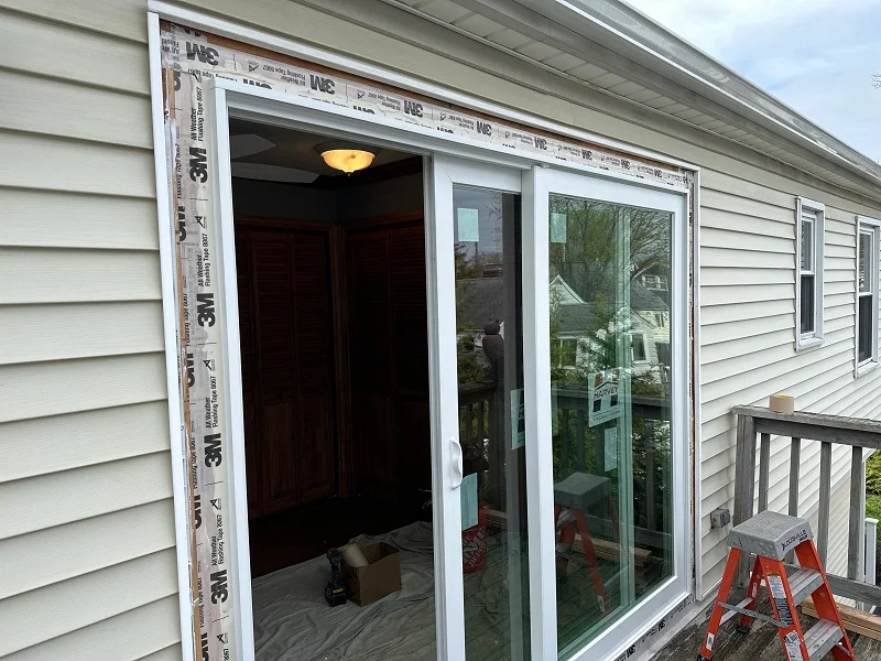 Removing vinyl siding to install this Harvey patio door in Milford
